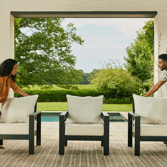 Stop-motion video of a man and a woman building a sofa. One black Edisto Aluminum Seat sits in the center of the frame, with the man and woman pushing in two additional chairs from each side. The three chairs connect to form and sofa, and the man and woman sit down. |ap